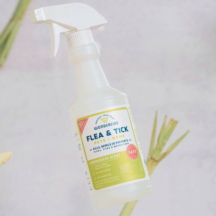 A bottle of Wondercide Apartment Treatment Kit | Flea & Tick Spray, made with natural essential oils and safe for pets, stands upright with lemongrass pieces in the background on a light surface.
