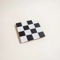Glass tile coaster by Subtler Art Co in black and white checkers at Clad, a sustainable clothing boutique in Asheville, NC.